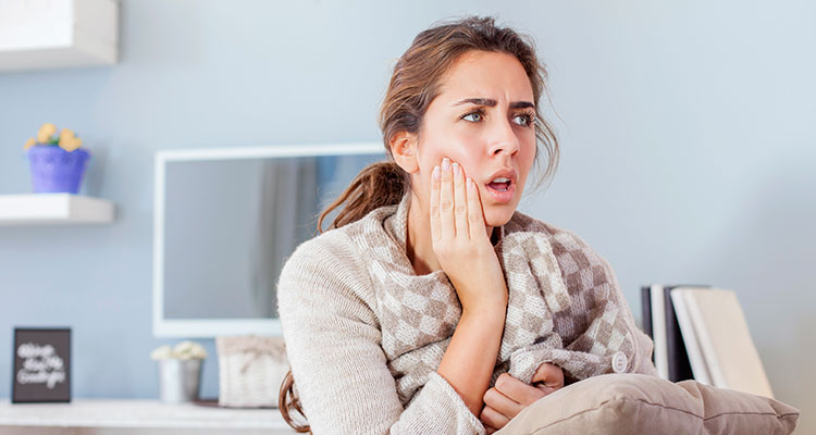woman holding her mouth due to pain caused by a tooth abscess